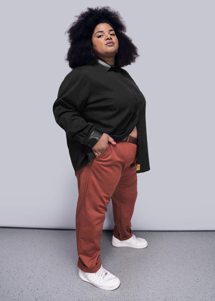 1X=Person wearing a black shirt and red pants against a gray background