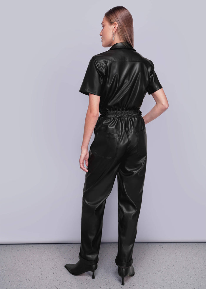 S=Back view of person wearing a black vegan leather jumpsuit against a plain background