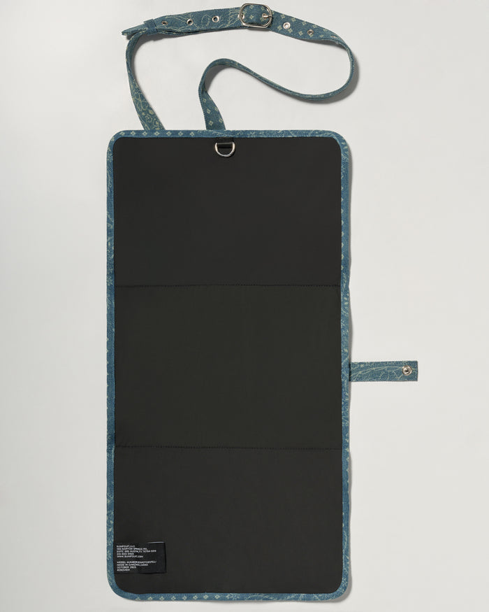 A denim roll up diaper change mat bag by Spell and Bumpsuit,, shown on a light gray background with wipes and diapers