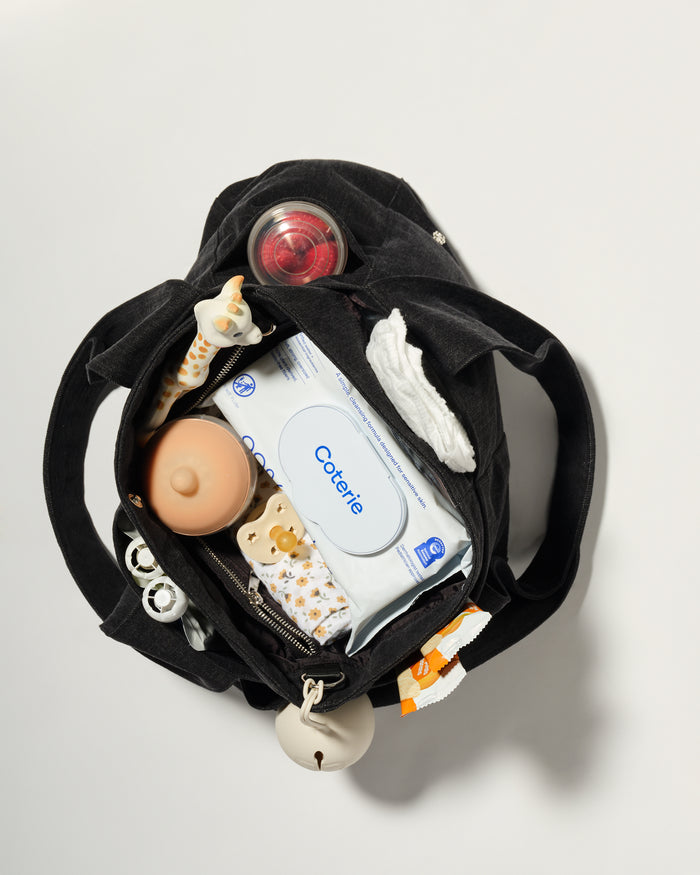A black diaper bag shown from above, open to reveal baby essentials inside
