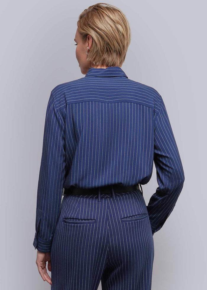 S=A model viewed from the back wearing a navy blue pinstriped shirt and matching trousers with a black belt, standing against a light gray studio background.