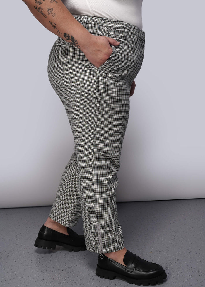 1X=Side view of person wearing plaid pants and black loafers on a plain background