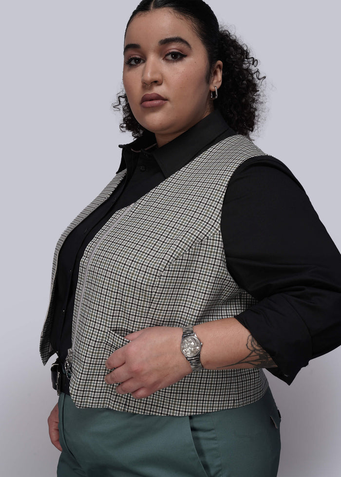 1X=Person wearing a checkered vest over a black shirt on a white background