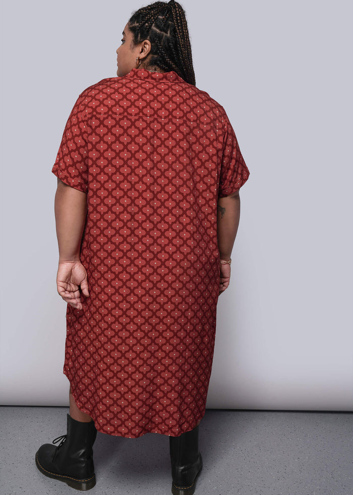 1X=Person wearing a red patterned dress against a plain background