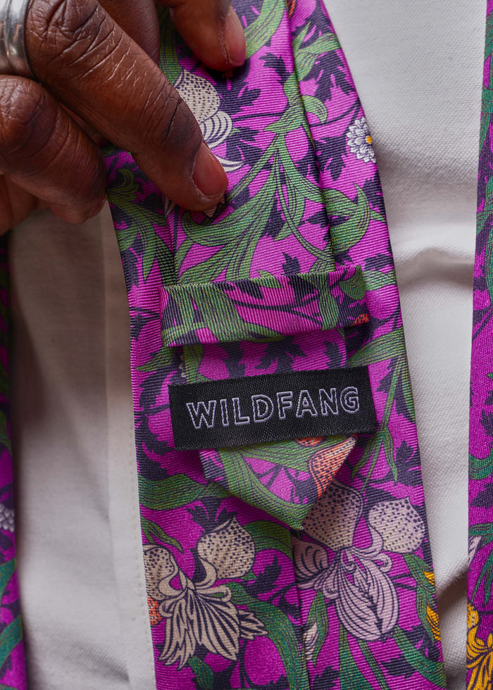 Floral-patterned tie with 'WILDFANG' label held by a hand
