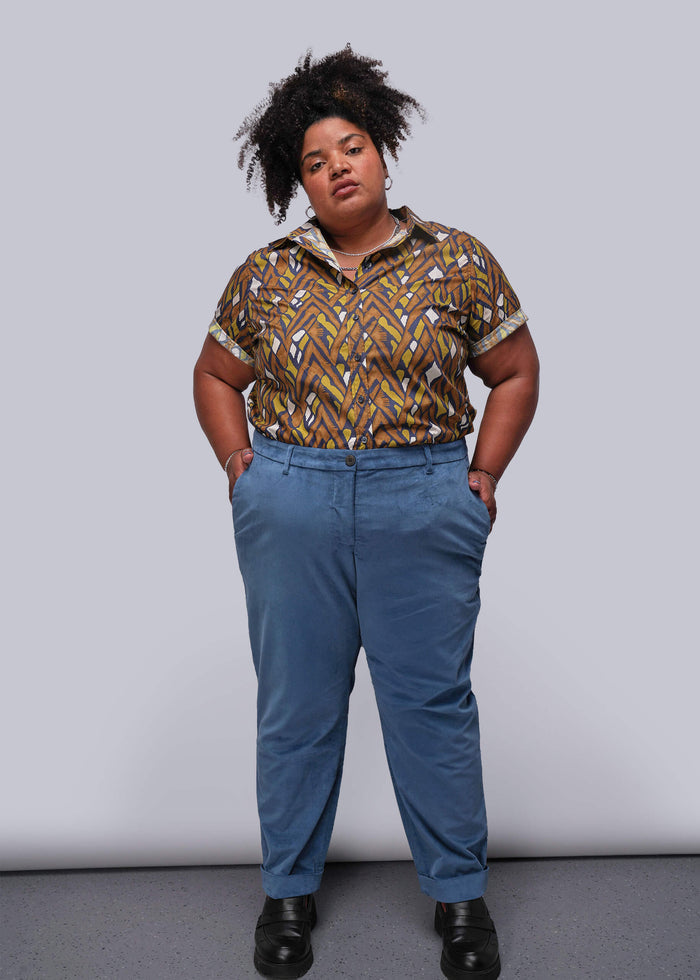 1X=Person wearing a patterned shirt and blue pants against a plain background