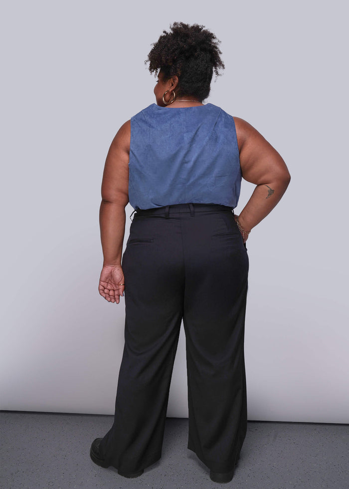 1X=Person wearing a blue sleeveless top and black pants against a plain background
