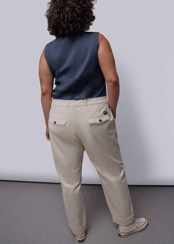 1X=Person wearing a navy sleeveless top and beige pants against a white background