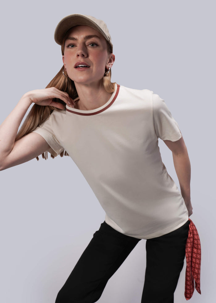 S=Woman wearing a white t-shirt with red trim and black pants against a light gray background