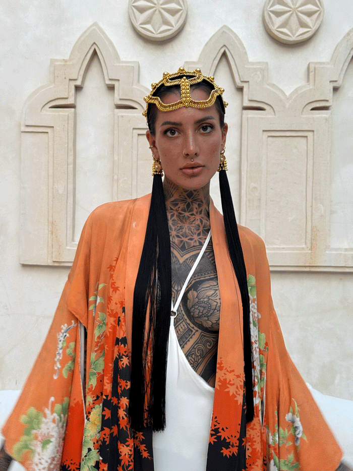 woman standing in unique bacground wearing Tamoe Silk Harness Skirt in White with Antique Kimono and Khutulun Headband gold with 22" long Tassel Gold-Black  by Object&Dawn