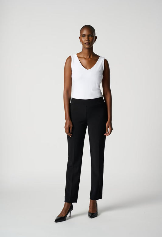 Woman wearing a white sleeveless top and black pants on a white background