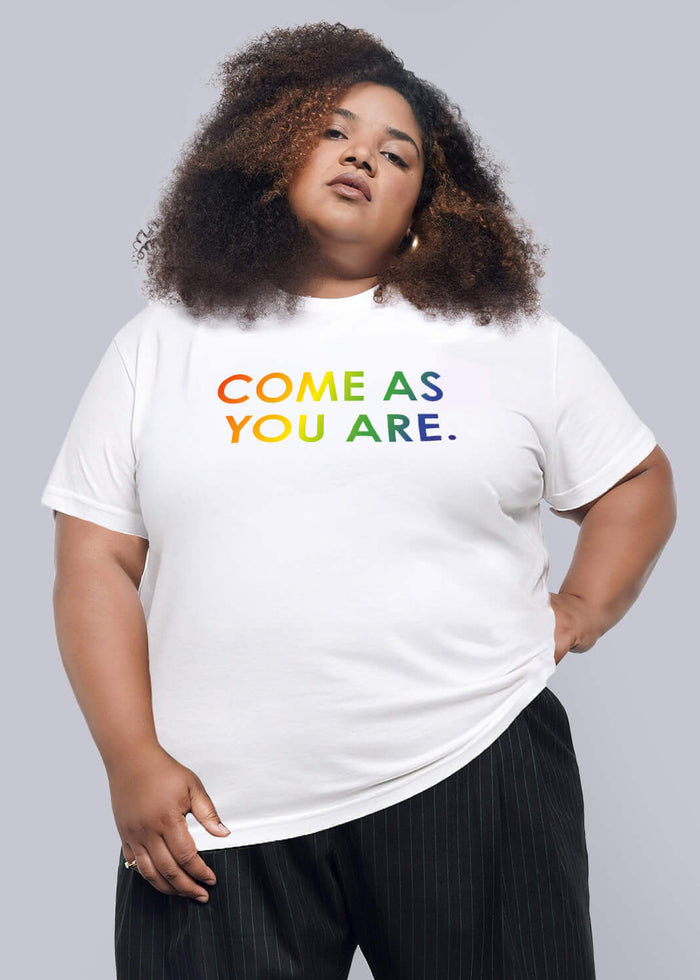1X=Person wearing a white t-shirt with colorful text and black pants on a plain background