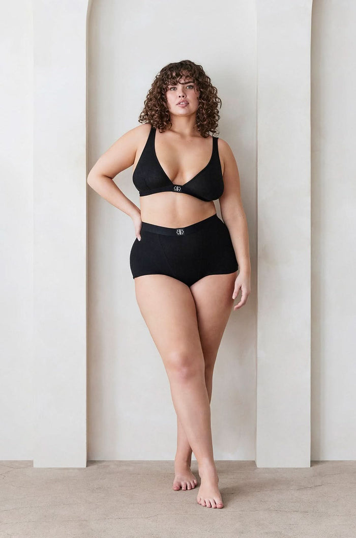 Plus size model wearing Bumpsuit Maternity The Cotton Rib Plunge Bralette & Boy Short in Black