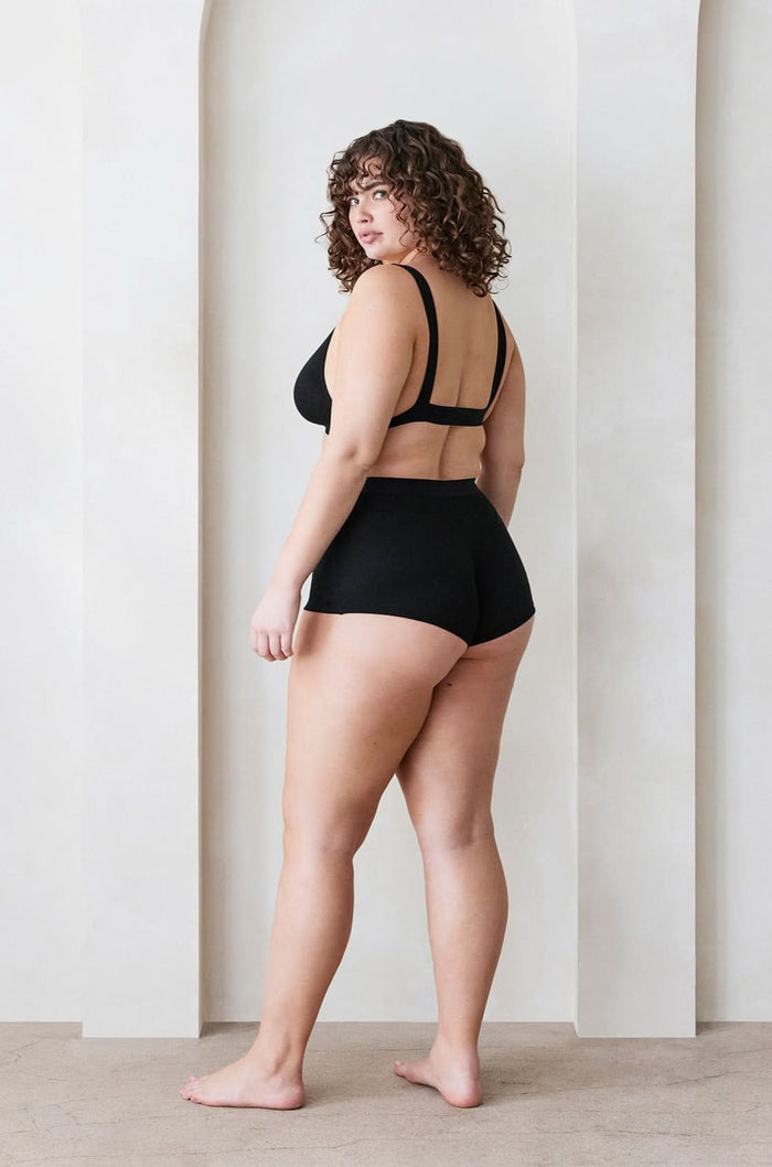 Back view of a model wearing Bumpsuit Maternity The Cotton Rib Plunge Bralette & Boy Short in Black