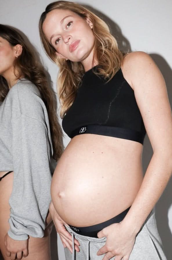 Pregnant model wearing the bumpsuit cotton rib crop top in black, with another woman in the background