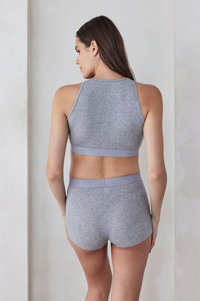 Back view of a pregnant woman wearing a grey cotton rib crop top and boy shorts set against a plain background
