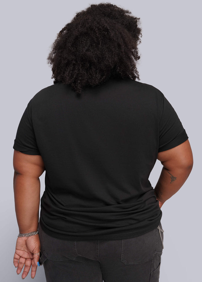1X=A person shown from the back wearing a black short-sleeve T-shirt and dark gray pants against a light gray studio background.