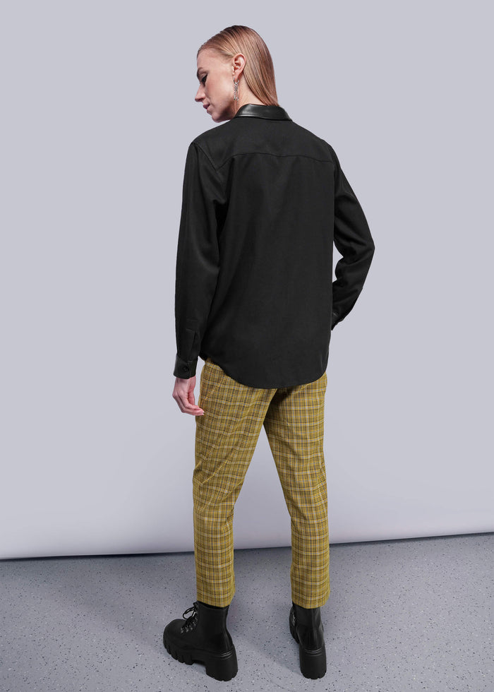 S=Person wearing a black shirt and yellow plaid pants against a gray background