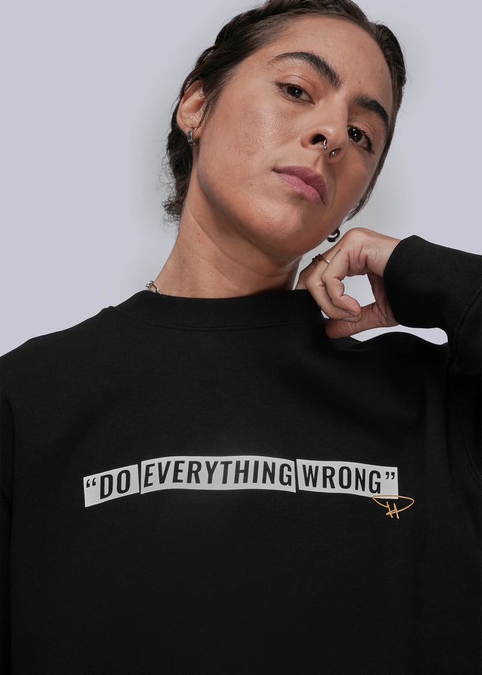 S=Person wearing a black sweatshirt with 'DO EVERYTHING WRONG' text on a plain background