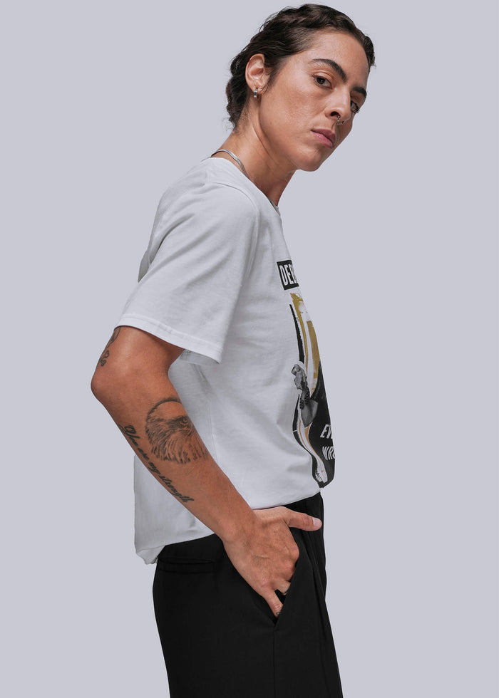 S=Person wearing a white t-shirt with a graphic design on a plain background