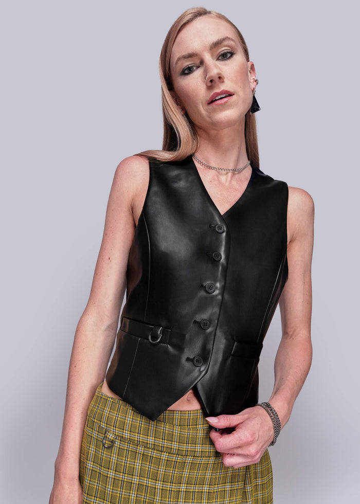 S=Peraon wearing a black vegan leather vest against a plain background