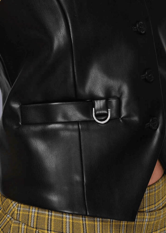 S=Close-up of a black vegan leather vest with a belt and plaid pants.