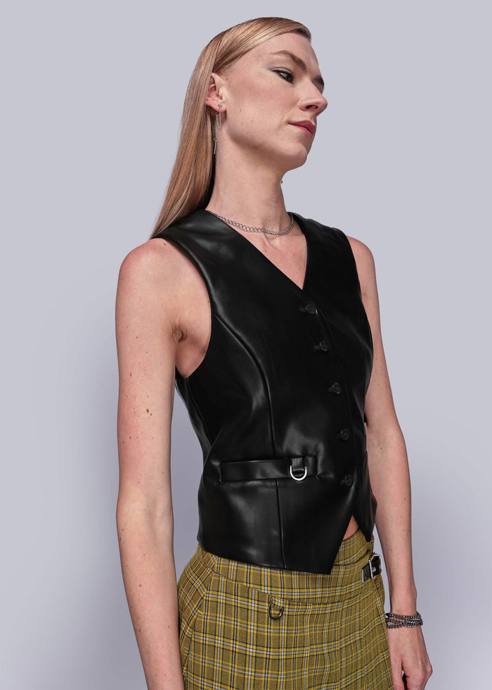 S=Person wearing a black vegan leather vest against a light gray background