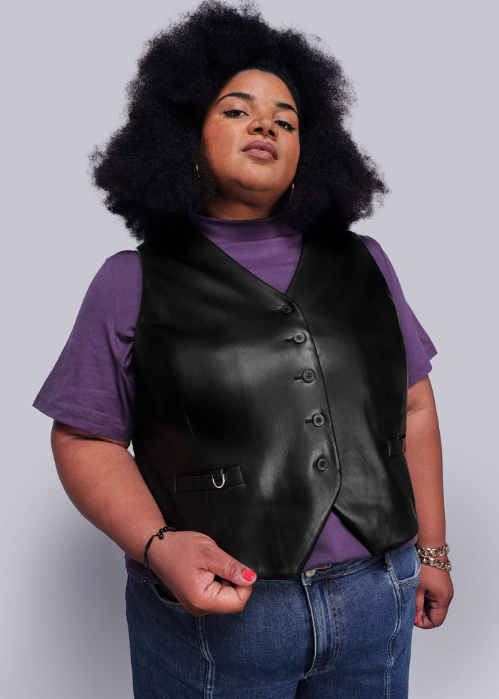 1X=Person wearing a black vegan leather vest over a purple shirt with a plain background