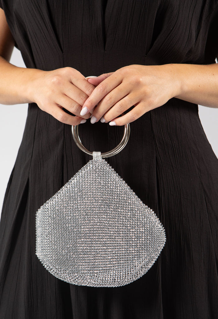 Silver beaded handbag held by a person wearing a black dress.