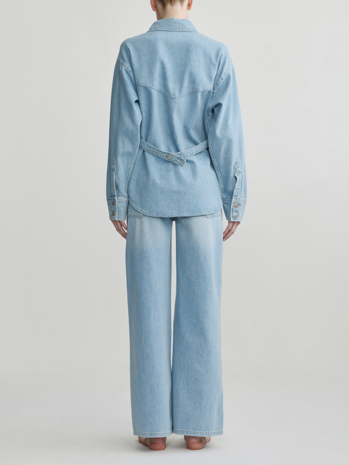 Person wearing a light blue denim outfit on a plain background