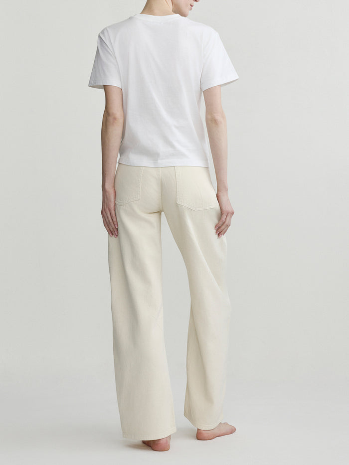 Back view of a person wearing a white t-shirt and beige pants on a plain background