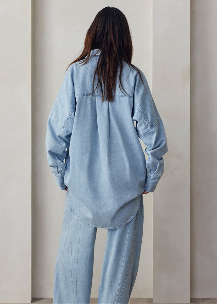 Person wearing a light blue denim outfit against a neutral background