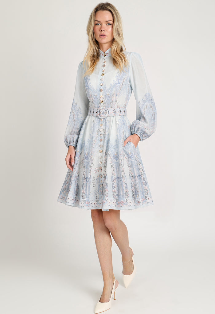 Woman wearing a light blue floral dress with a belt on a white background