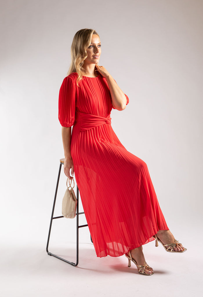 Woman in a red dress sitting on a chair against a white background