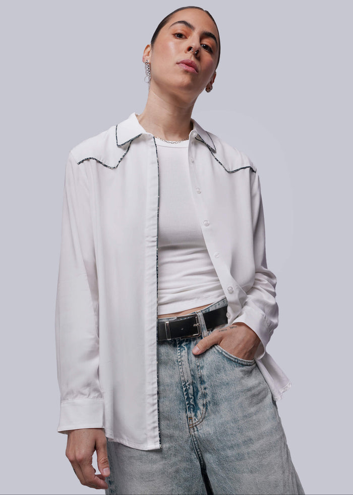 S=Person wearing a white button up shirt over a white top with jeans on a plain background