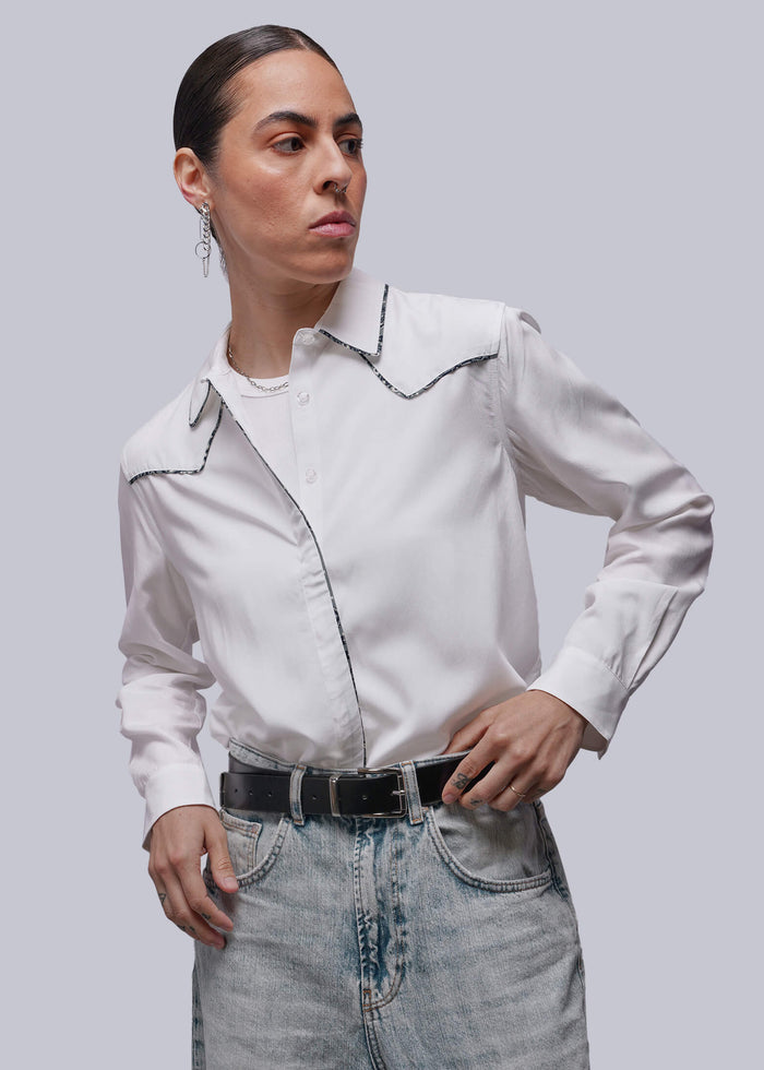 S=Person wearing a light-colored shirt with dark accents and jeans on a plain background