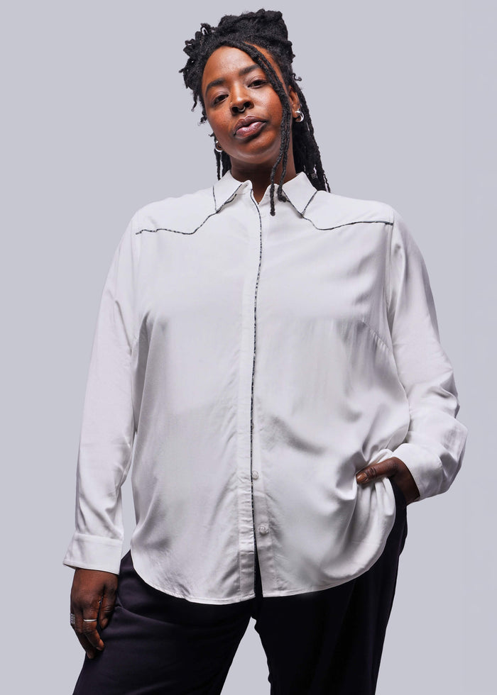 1X=Person wearing a light-colored shirt with a subtle pattern on a plain background