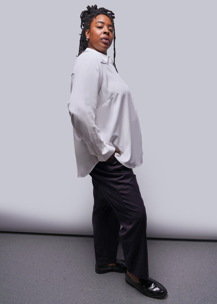 1X=Person wearing a white button up shirt and black pants against a plain background