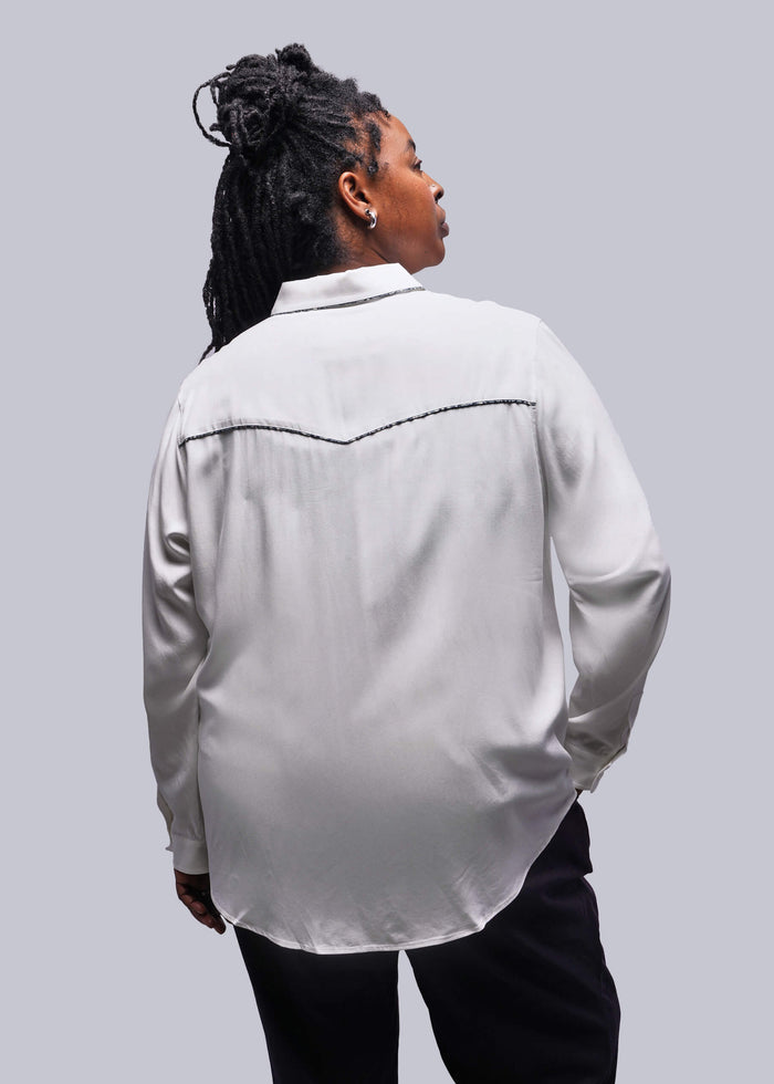 1X= Back of person wearing a white button up shirt against a plain background