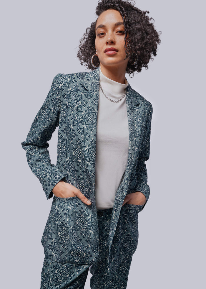 S=Person wearing a patterned blazer and pants on a plain background