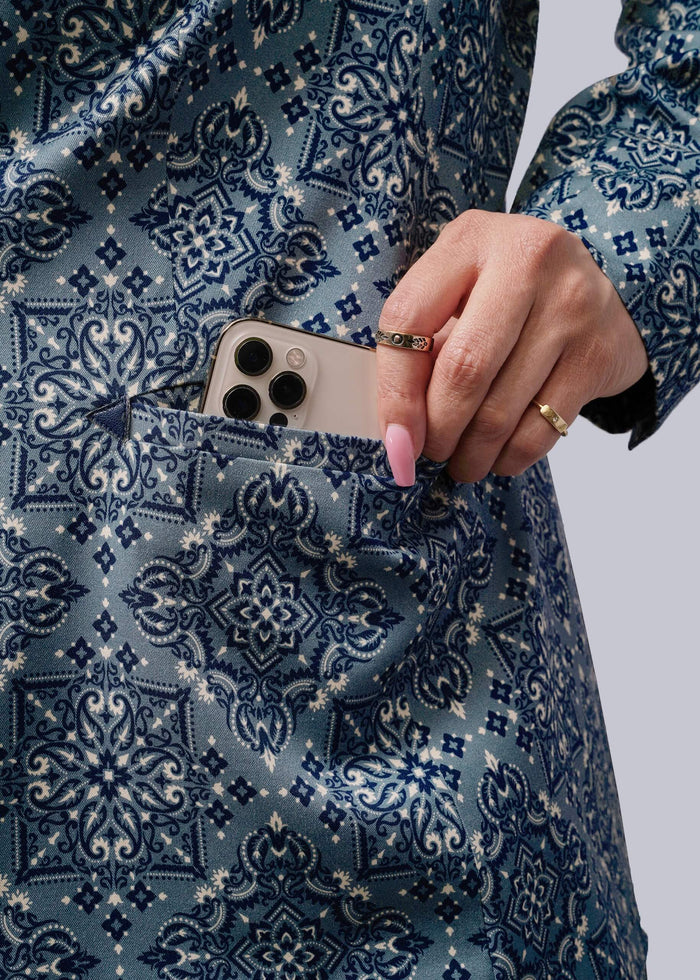 S=Close up of person placing a phone in a pocket of a blue patterned blazer
