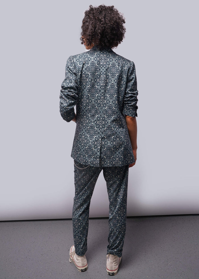S=Back of person wearing a patterned suit standing against a plain background