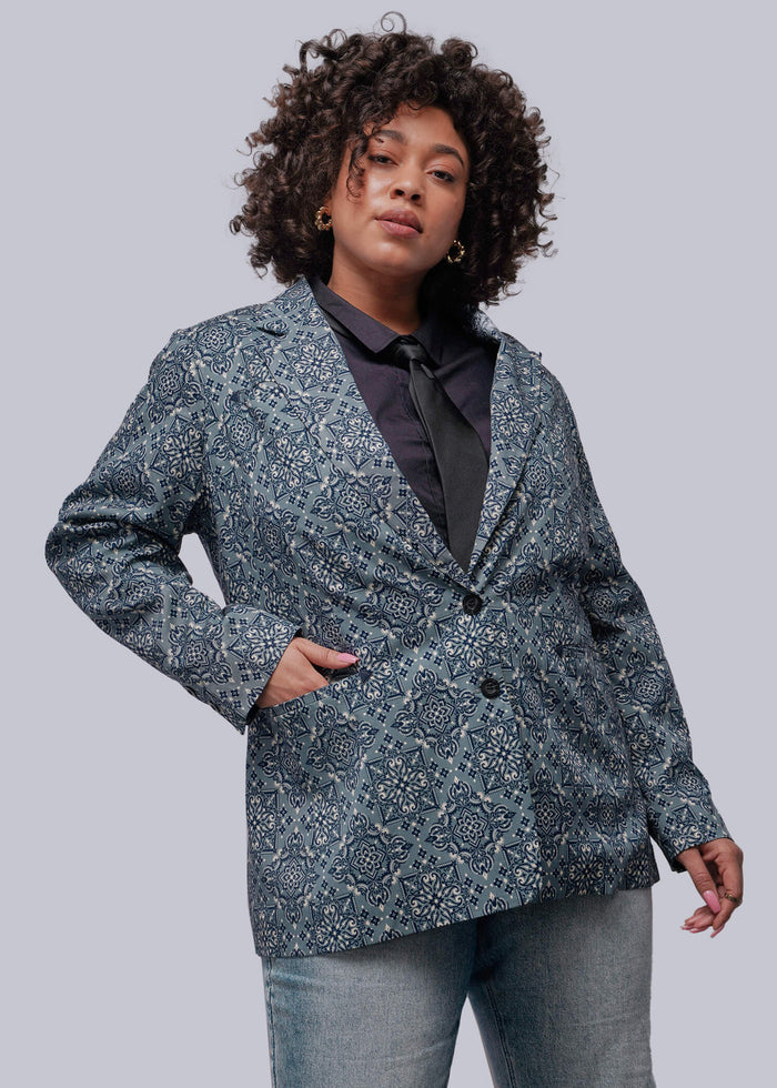 1X=Person wearing a patterned blazer and jeans on a plain background