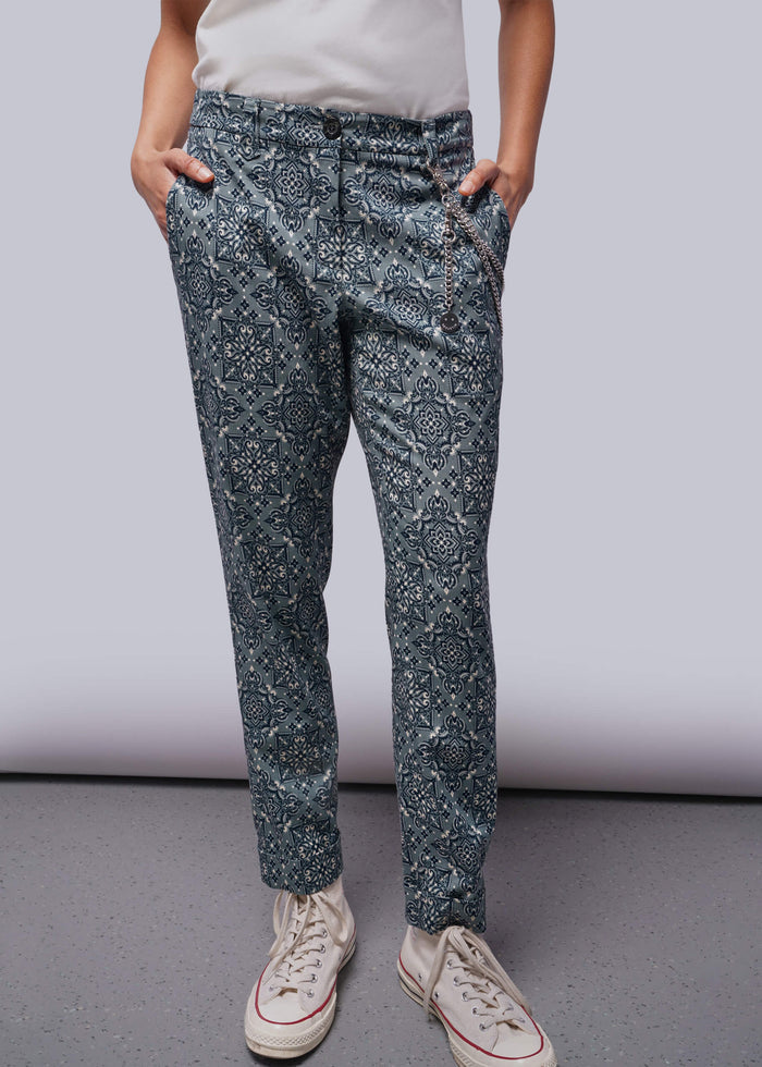S=Person wearing blue patterned pants and white sneakers on a plain background