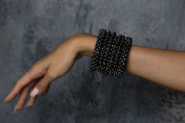 hand of person with handcrafted modular cuff in jet black from hundreds of beads by object and dawn