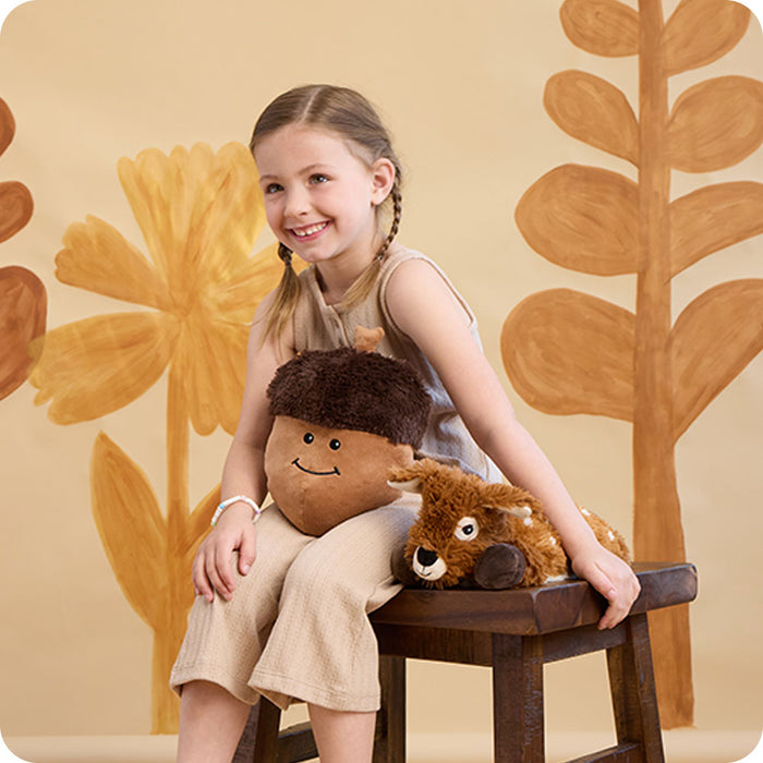 girl sitting on bench with laying down deer stuffed animal warmies