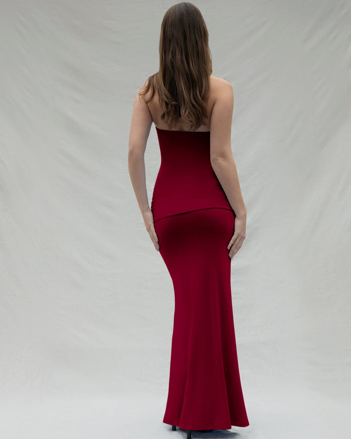 backview of a woman wearing a burgundy maxi Bumpsuit dress on a white background