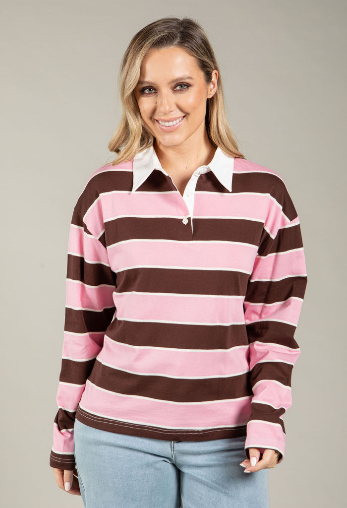 Woman wearing a pink and brown striped long-sleeve shirt against a neutral background