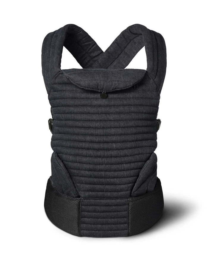 A Bumpsuit black denim quilted baby carrier with a textured fabric body, black mesh waist belt, and adjustable shoulder straps, with leg guards shown on a white background with a soft shadow.