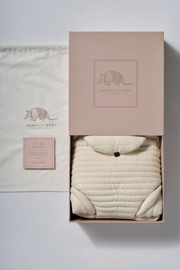 Bumpsuit ivory colored armadillo Baby carrier in a box next to a carrier bag